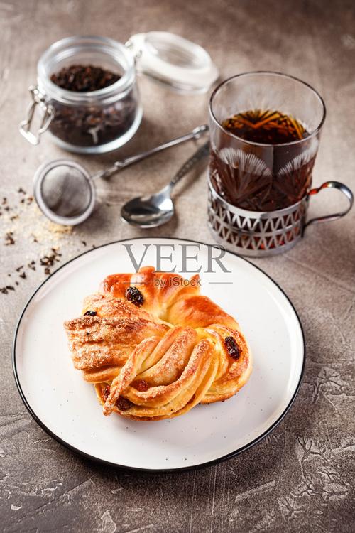 甜馅饼或面包由酵母面团制成放在盘子和一杯茶上